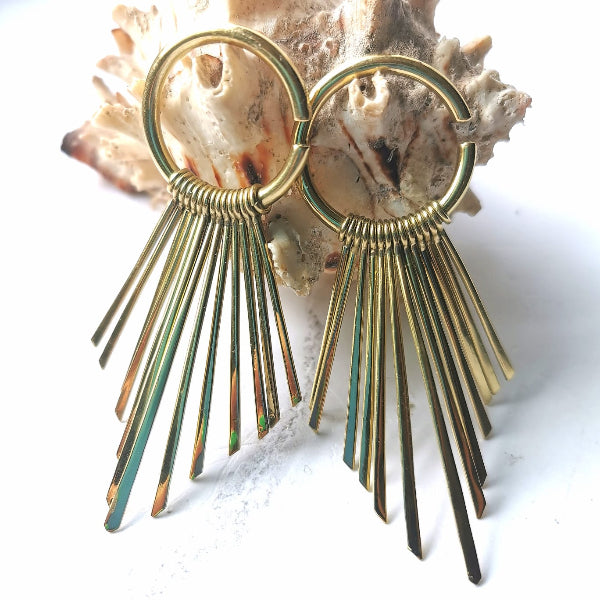 Gold hoop earrings with fan-shaped designs on a shell background