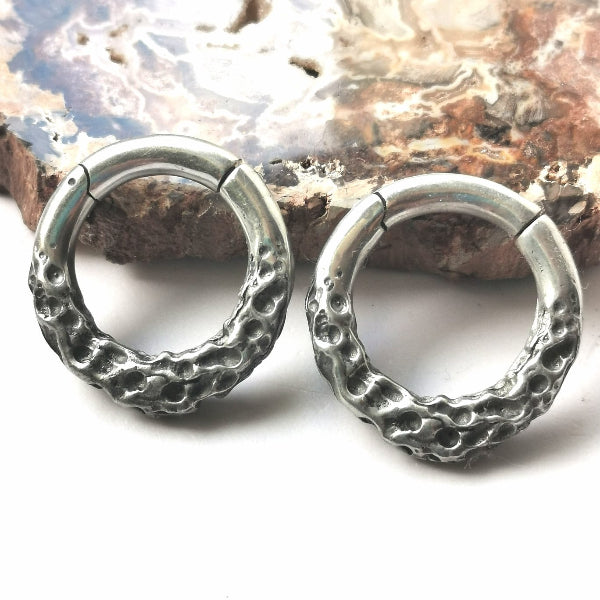 Pair of silver hoop earrings on a stone surface