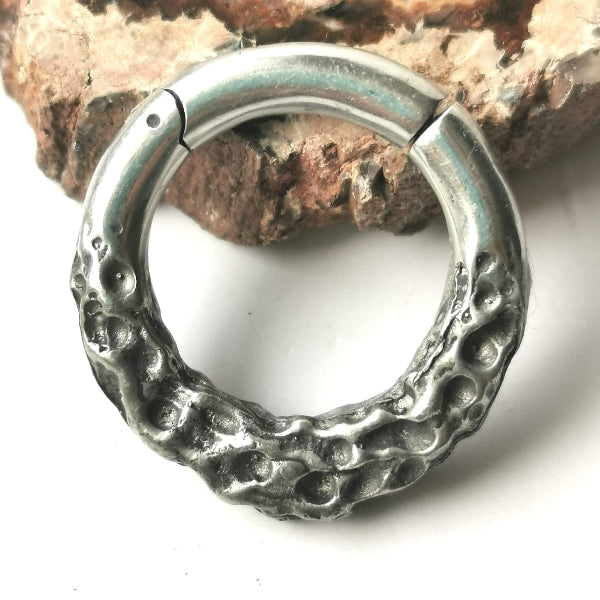 Silver hoop earring on a white background with a rock in the background