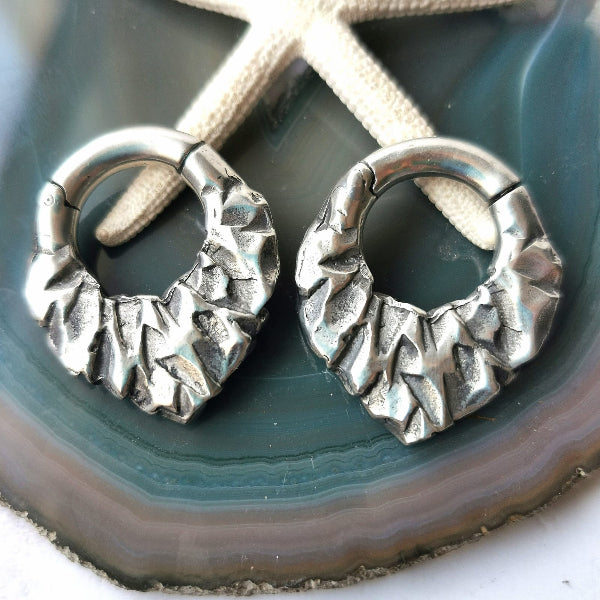 Pair of silver hoop earrings on a textured surface