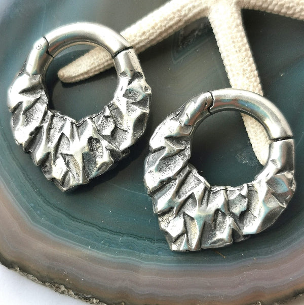 Pair of silver hoop earrings on a textured surface