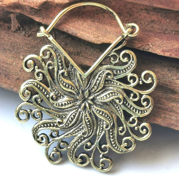 Floral gold earring on a wooden surface