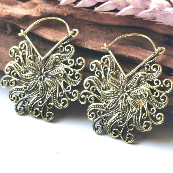 Pair of gold floral earrings on a wooden surface