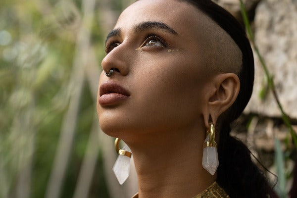 Brass ear weights with white quartz crystals on model with stretched ears