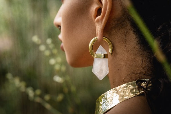 Brass ear weights with white quartz crystals on model with stretched ears