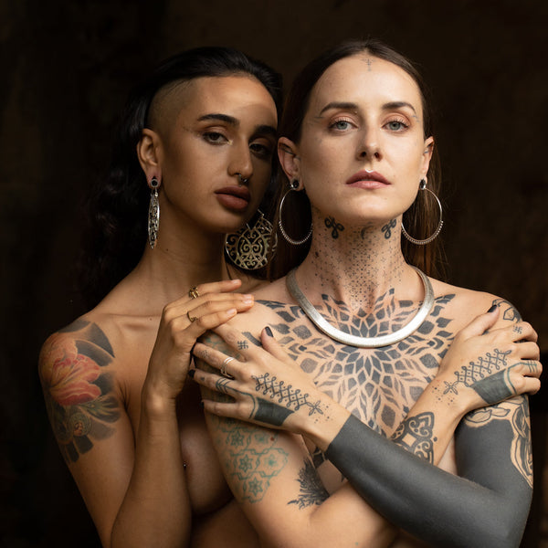 Two tattooed models wearing hoop earrings designed by Tribalik