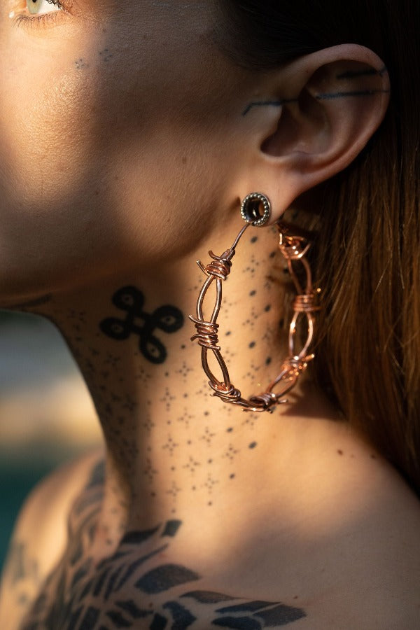 18k rose gold plated brass earrings - ear weights with barbed wire - Pua on model wearing tunnels